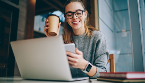 Image showing a female worker enjoying working on her laptop and phone representing an enhanced user experience